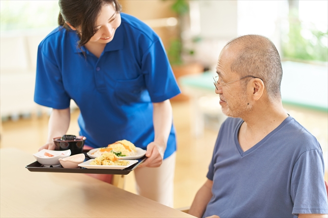 高齢者に食事を提供する介護スタッフ
